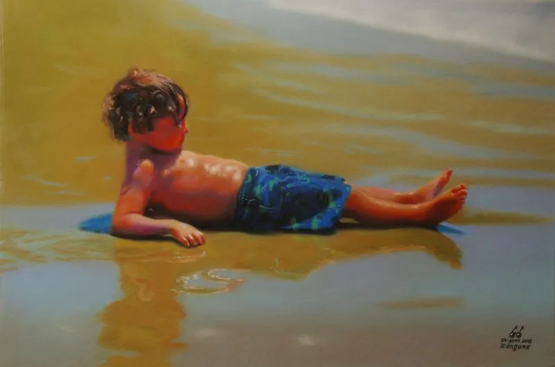 Niño pequeño tendido sobre la arena mojada, a la orilla del mar.