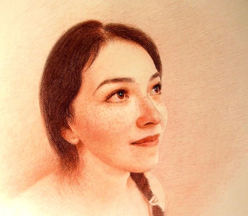 Retrato de una joven con pecas y cabello castaño oscuro, mirando hacia arriba, sobre papel de tono cálido.